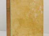 an old book with a yellow cover sitting on a white surface