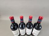 four bottles of red wine are lined up on a table