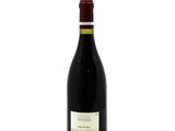 the bottle of red wine is sitting on a white surface