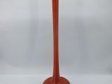 an orange glass vase with a long stem sitting on a white surface