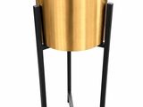a gold planter on a black stand with a white background