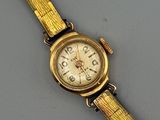 an image of a gold wrist watch with a white face on a gray surface