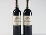 two bottles of red wine sitting next to each other on a white surface