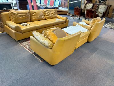 un canapé en cuir jaune et un fauteuil dans une pièce