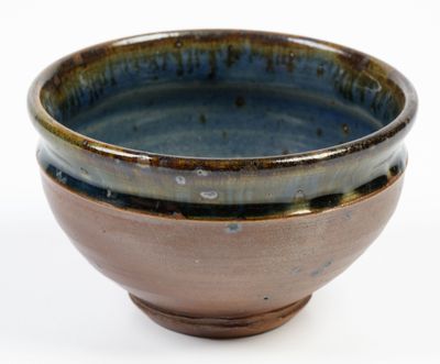 a brown and blue bowl sitting on a white surface
