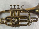 a brass trumpet that is sitting on a white surface