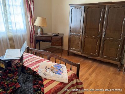 a bed with a red and white bedspread next to a wooden dresser