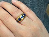 la main d'une femme tenant une bague sertie d'une pierre bleue