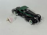 a black toy car with a green top on a white surface