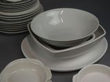 a lot of white plates and bowls on the table