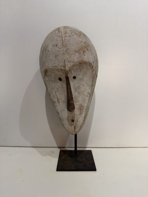 a sculpture of a mask on a stand on a white surface