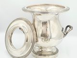 une coupe ancienne en métal argenté avec un couvercle, posée sur un socle