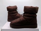 une paire de bottes d'hiver marron posée sur une boîte blanche