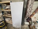 a white refrigerator in a garage next to a shelf of other items