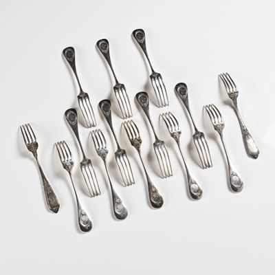 Plusieurs fourchettes et cuillères sont disposées en rangée sur une surface blanche