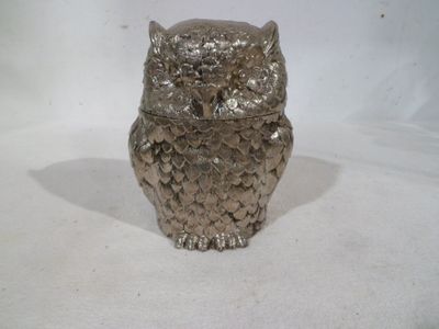a silver owl figurine sitting on a white surface