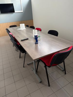 des tables et des chaises dans une pièce où est accrochée une télévision à écran plat au mur