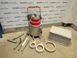 une photo d'un aspirateur rouge et argent posé sur un sol en béton