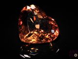 an orange diamond on a black surface in the dark