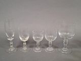 six empty wine glasses lined up on a gray surface