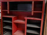 une armoire rouge avec des étagères et un tableau accroché au mur