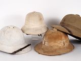 Plusieurs chapeaux sont alignés sur une surface blanche