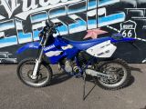 a blue and white dirt bike parked in front of a graffiti covered wall