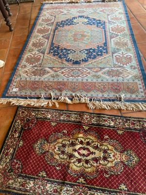 deux tapis posés à même le sol dans une pièce où se trouvent une chaise et une table
