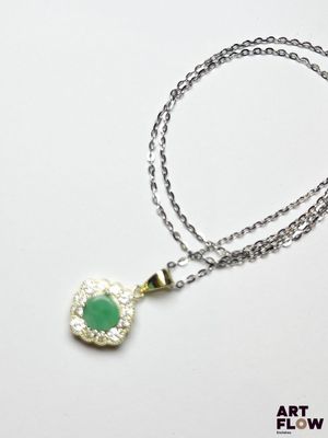 un gros plan d'un collier composé d'une pierre verte montée sur une chaîne