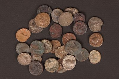 some old coins are scattered on a black surface with a small amount of them