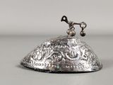 an antique silver bell with a bird on top of it