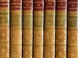 several old books are lined up on a shelf in a library