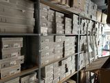 boxes are stacked on a shelf in a warehouse with people walking by