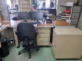 a desk with two computer monitors and a filing cabinet