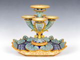 un vase bleu et jaune sur lequel sont posées trois bougies