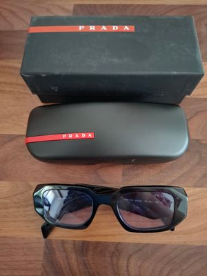 Lunettes de soleil Prada noires avec bordure rouge et étui