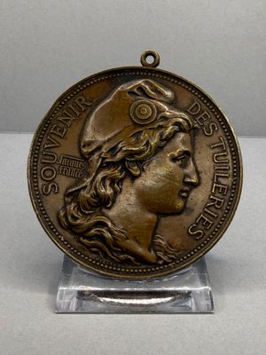 une vieille médaille en bronze représentant le visage d'une femme coiffée d'un chapeau