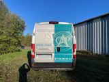 the back of a white van parked in a field next to a building