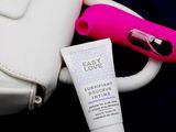 a white bag with a pink handle and a tube of cream next to it