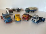 Plusieurs camions miniatures sont alignés en cercle sur une surface blanche