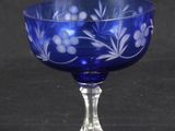 blue glass goblet with white flowers on it on a black background