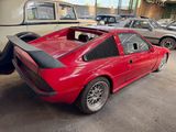 a red car parked in a garage with other cars in the background