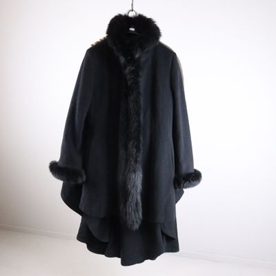 a black coat with a fur collar is hanging on a hanger