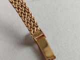 a close up of a gold bracelet on a white surface