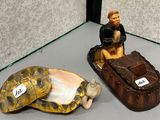 deux figurines représentant un homme assis sur une carapace de tortue