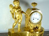 a gold clock with a statue on it on a table