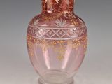 un vase en verre rose orné d'un motif doré
