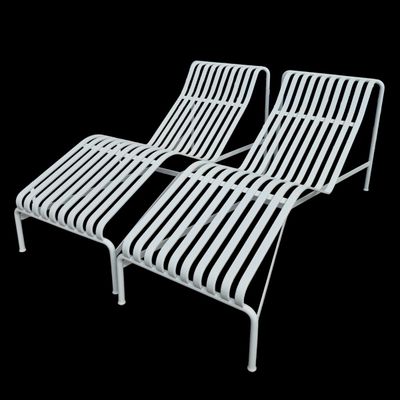 pair of white metal lounge chairs on a black background