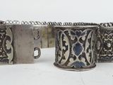 three antique silver bracelets on a white surface with a white background