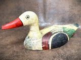a wooden duck with a red beak on a brown surface